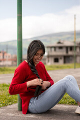 Fototapeta premium Young smiling Hispanic girl having her hair braided, relaxation concept