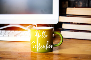 Hello September concept on coffee cup, desktop: laptop keyboard and books