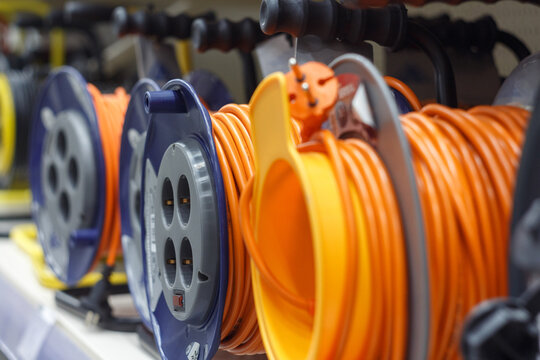 Extension cords on a spool with an orange cable in a store, selective focus.