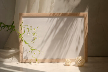 Interior still life with geometric shapes, picture frame with paper sheet, gypsophila flowers....