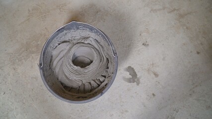 Worker mixes the mortar. Worker's hands mixing grout for filling space between ceramic tiles. A worker fills a bucket with mortar.