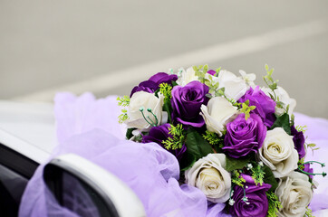 White and purple flowers in a bouquet on a white wedding car close-up. High quality photo