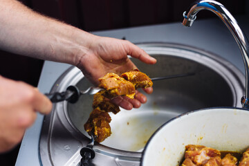 The chef stringing meat on skewers for cooking