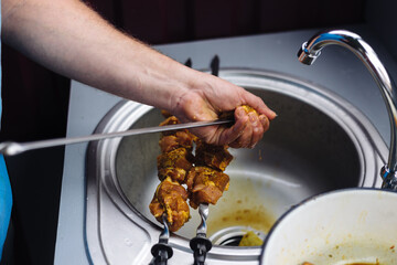 The chef stringing meat on skewers for cooking