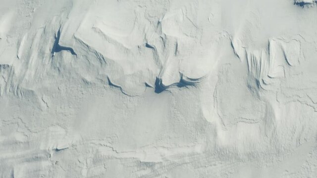 White background of snow texture, aerial view. Birdseye drone shot flying over snow covered frozen field. 
