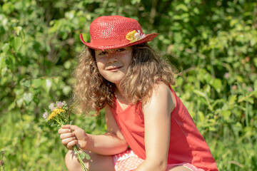 Porträt eines jungen, hübschen, manchmal nachdenklich oder frechen, Blumen pflückendem Mädchens.