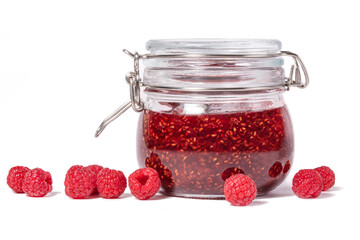 A jar of raspberry jam with fresh raspberries on a white background.