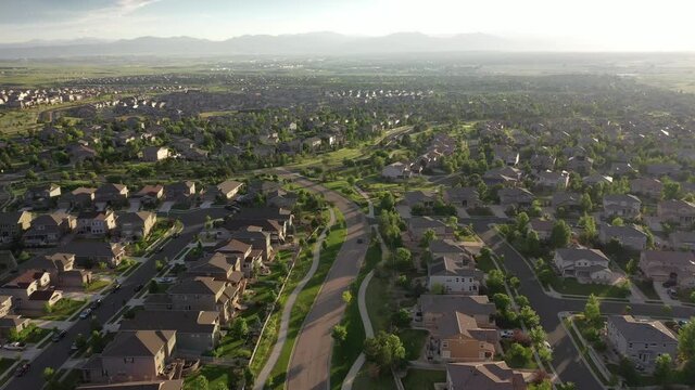 Dynamic aerial video of suburban housing developments sprawling across flat plain with mountains in distance