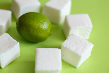Natural and homemade marshmallows and limes on green background