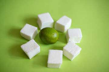 Natural and homemade marshmallows and limes on green background
