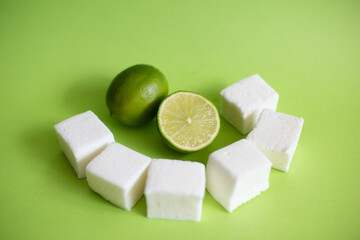 Natural and homemade marshmallows and limes on green background