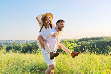 Happy laughing adult couple having fun outdoors, nature sky background