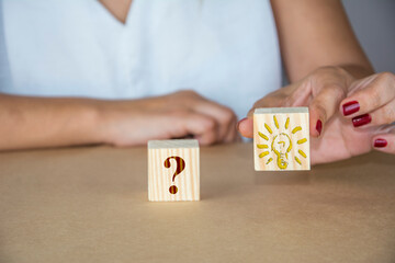 Unrecognizable woman highlights wooden cube with idea symbol