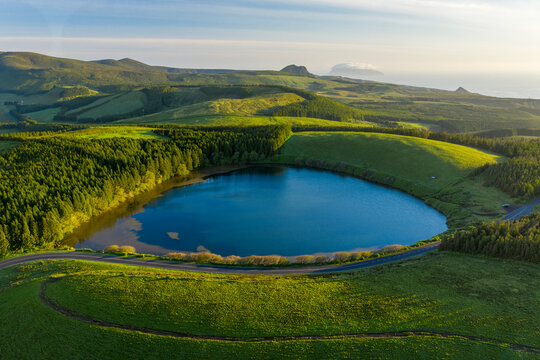 Aerial view of Lagoa da Lomba, a small lake surrounded with vegetation at sunset on Ilha das Flores, Azores islands, Portugal.