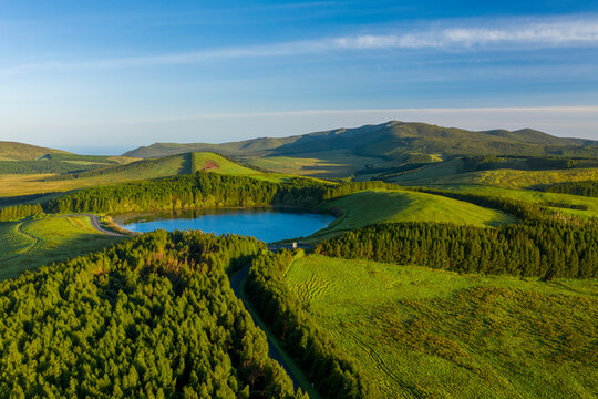 Aerial view of Lagoa da Lomba, a small lake surrounded with vegetation at sunset on Ilha das Flores, Azores islands, Portugal.