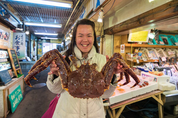 Pretty Young Asia Tourist girl holding huge and the most famous food King Crab fresh seafood market...