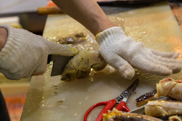 Sushi chef wearing white grove cutting King Crab of Hokkaido, Japan