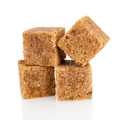 Cubes of dark brown sweet sugar from cane, isolated on a white background, macro