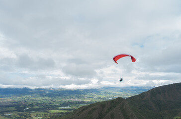 Paraglider tandem fly with blue sky,tandem paragliding over the mountains in a cloudy day

