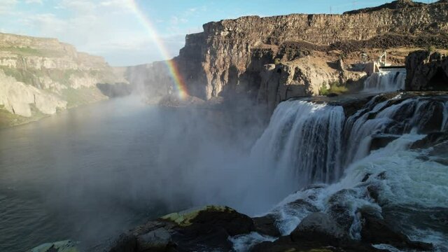 Epic drone video flying low over large waterfall cascade with rainbow in canyon