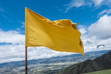 Close up attention yellow flag on blue sky over a mountain
