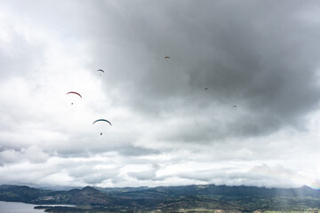 Paraglider tandem fly with blue sky,tandem paragliding over the mountains in a cloudy day
