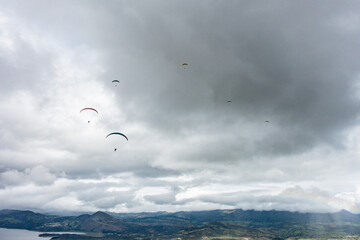 Paraglider tandem fly with blue sky,tandem paragliding over the mountains in a cloudy day
