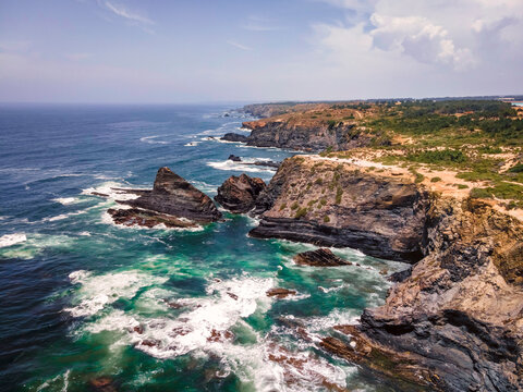 Aerial view of rough sea waves along the coastline in Odeceixe, Faro, Portugal.