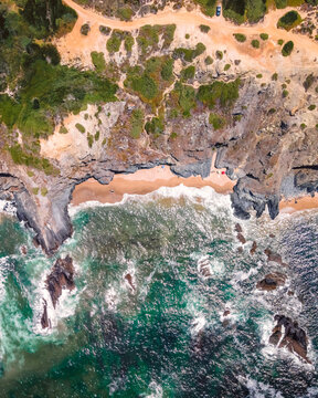 Aerial view of rough sea waves along the coastline in Odeceixe, Faro, Portugal.
