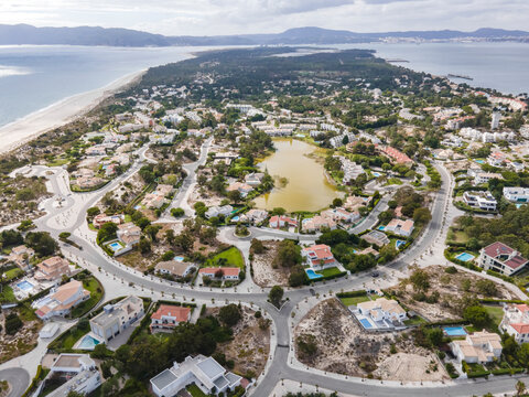 Aerial view of an exclusive luxury village with expensive villas and hotels on Troia Peninsula along the beach with artificial lake, Setubal, Portugal.