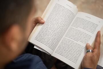 Naklejka premium close-up detail of a book being held by the hands of an adult man