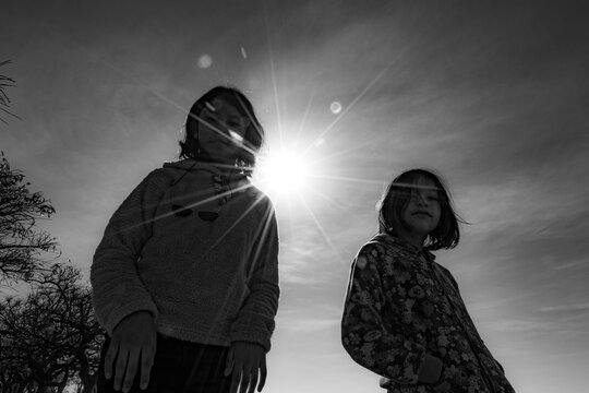 ni&ntilde;as hermanas adolescentes bajo fuerte sol a contraluz mirando hacia el suelo