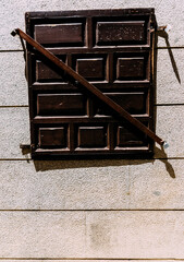 Vertical shot of a window bolted shut with wood, on a stone building
