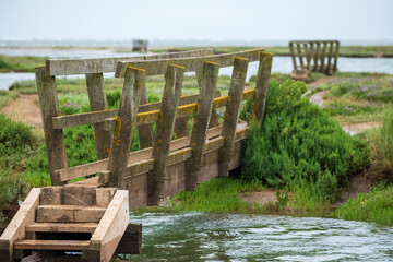 Wooden pedestrian bridges in the salt marshes at Stiffkey near Holt in North Norfolk, East Anglia...