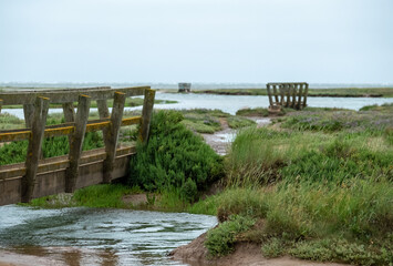 Wooden pedestrian bridges in the salt marshes at Stiffkey near Holt in North Norfolk, East Anglia...