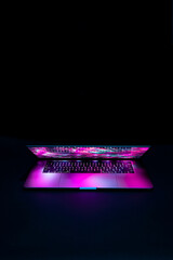 Isolated high tech open laptop with abstract vibrant color screen on a dark background.