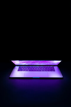 Isolated high tech open laptop with abstract vibrant color screen on a dark background.