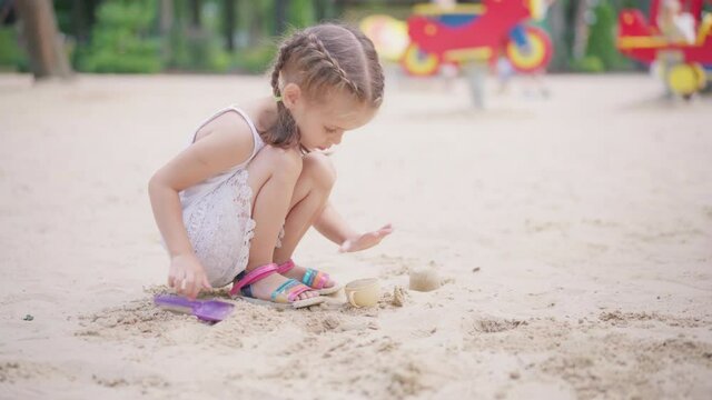 Little Girl Playing Sandbox Playground Digging Sand Shovel Building Sand Figure Summer Day. Caucasian Female Child 5 years Have Fun Outdoor 