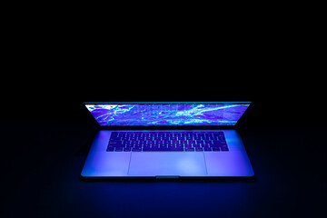 Isolated high tech open laptop with abstract vibrant color screen on a dark background.