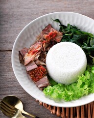 Se'i Sapi or  Beef Sei is Indonesia Traditional Smoked Beef, Served with Boiled Cassava Leaves and Sambal Luat or Sambal Matah. Typically Food from Nusa Tenggara, Indonesia