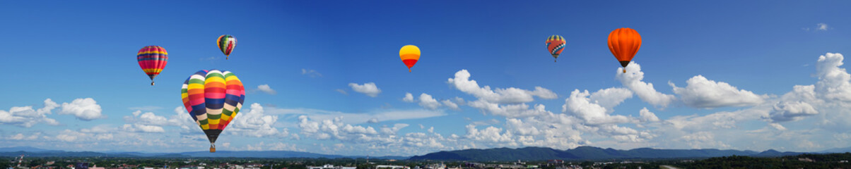 panorama of color hot air balloons in blue sky over the city background.