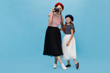 Full length photo of two modern girls with ginger hair in berets, striped t-shirt and fluffy midi...