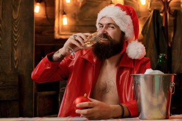 Bearded handsome Santa Claus smile and drink champagne. Christmas lights garland. Merry christmas and happy new year. Christmas gifts. Santa waiting for New Year midnight.
