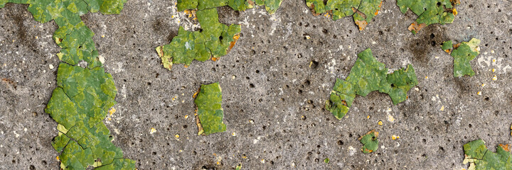 Green peeling paint on the wall. Old concrete wall with cracked flaking paint. Weathered rough painted surface with patterns of cracks and peeling. High resolution texture for background and design.