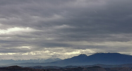 Fototapeta na wymiar Nuvole grigie sopra le cime innevate dei monti Appennini