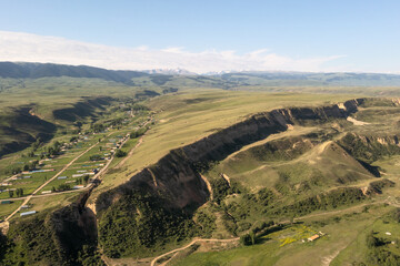 Naklejka premium Mountain peaks and grassland are under white clouds.