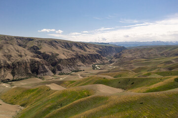 Fototapeta premium Mountain peaks and grassland are under white clouds.