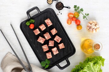 Top View Raw Saikoro Wagyu Cubes Beef Steak on Steak Plate with Lettuce at Background, Above White Table with other Spice at Background