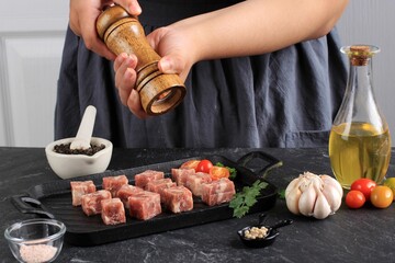 A Woman Cooks with Salt and Black Pepper Fresh Raw Saikoro Diced Steaks from Marbled Japanese Beef on a White Kitchen Background.