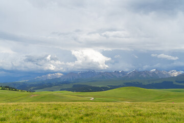 Grassland and mountains in a cloudy day. Photo in Kalajun grassland in Xinjiang, China.